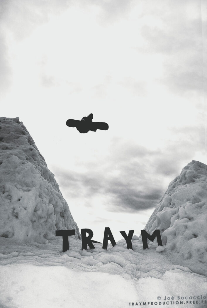 Snowboarder effectuant une figure sur un big air avec les lettres « TRAYM » en arrière-plan - Photographe de sport outdoor et station de ski, Annecy, Rhône-Alpes.